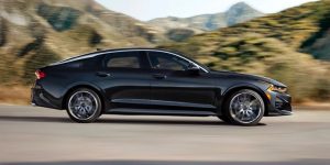 right side profile of a black 2023 Kia K5 in motion on a road | Frederick, MD