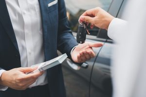 Closeup hand giving a car key and money for loan credit financial, lease and rental concept | Frederick, MD